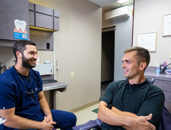 patient smiling at team member while laying in dental chair in Worcester